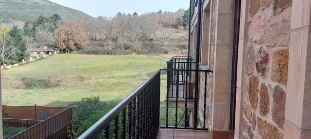 El balcón corrido sobre el prado, con el muro de piedra del edificio
